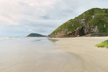 Serene Beach with Rocky Hill and Overcast Sky