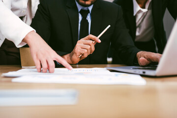 Business team collaborates over documents and a laptop, discussing strategies and ideas in a...