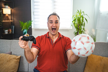 Middle age Caucasian man playing soccer video game at home