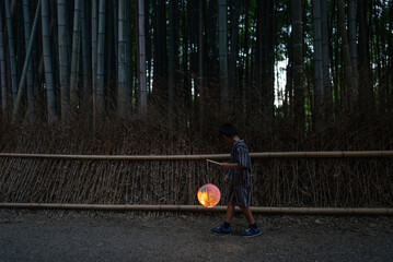 行灯を持って京都の竹林小径を歩く少年