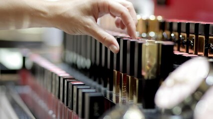 A young woman in a cosmetics store carefully selects products from the shelves. The concept of shopping, discounts and professional cosmetics.