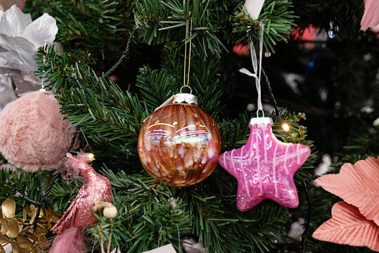 Colorful decorative Christmas ornaments in a box filled with pink shades.
