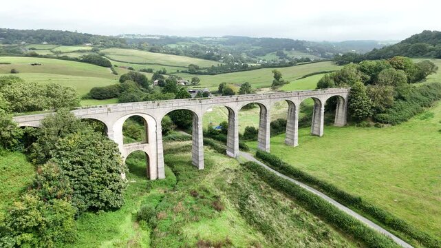 Aerial footage of Cannington Viaduct surrounded by greenery under cloudy sky in Dorset, England