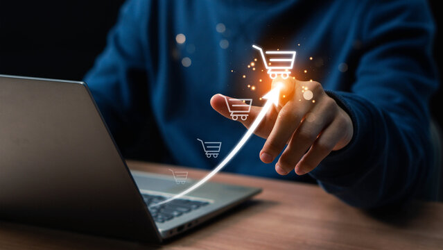 Businessman hand touching to virtual info graphics with trolley cart icons. Increase higher sale volume, shopping trolley cart for online e-commerce business. Online shopping business concept.