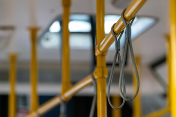 Flexible gray handles on yellow bus handrail.