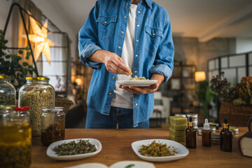 close up of man herbalist hands hold plate with dried herbs