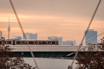 Train Crossing the City Skyline at Sunset - Urban Landscape, Cityscape, Skyline, Urban Transport, Public Transport, Train, Subway, Metro, Bridge, River, Water, Sunset, Twilight, Evening, Dusk