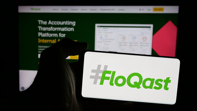 Stuttgart, Germany - 10-31-2024: Person holding mobile phone with logo of American accounting software company FloQast Inc. on screen in front of web page. Focus on phone display.