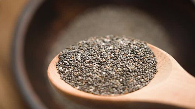 Chia seeds spilling from a wooden spoon. Nutrient-rich superfood high in omega-3 fatty acids, fiber and antioxidants. Perfect for healthy diets and nutrition