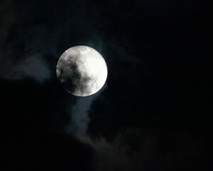 Full bright moon is overshadowed by dark gray clouds
