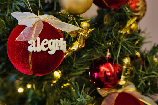 A red ball with the name Alejandra written on it hangs on a Christmas tree