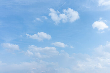 Beautiful fluffy white clouds drift across a bright blue summer sky