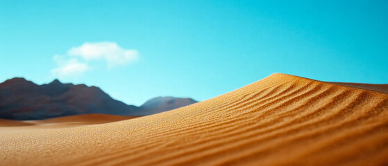 A serene desert landscape featuring golden sand dunes under a clear blue sky, with distant mountains adding depth to the scene.