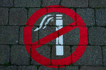 Znak, symbol zakazu palenia namalowany na chodniku.