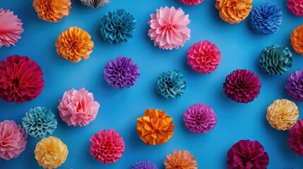 Fototapeta premium Vibrant paper balls scattered on a festive blue backdrop, perfect for birthday party or carnival invitations, featuring ample copy space from a top view perspective.