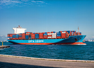A large container ship navigating through the ocean under a clear blue sky, loaded with shipping containers, representing global trade, logistics, and maritime transportation.