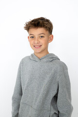 cool young 12 year old boy with grey hoody sweater posing in front of white background, having fun