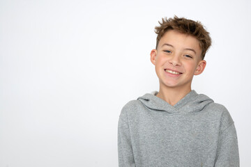 cool young 12 year old boy with grey hoody sweater posing in front of white background, having fun