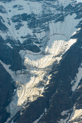 A stark view of a massive glacier sliding down a rocky mountainside. Caucasus Mountains