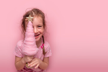 Close up portrait of cheerful young girl with braided hair holding golden star decoration against...