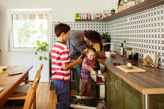 Father teaching kids to load the dishwasher as part of family chores
