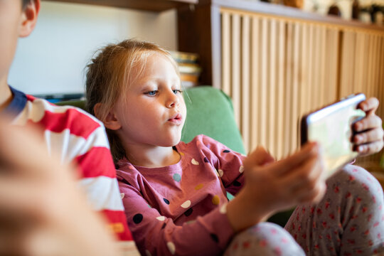 Young girl focused on smartphone screen while playing video games