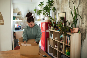 Young woman opening package in cardboard box at home