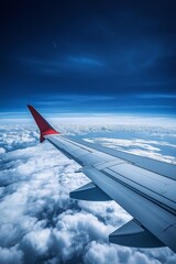 Fototapeta premium A red airplane wing is flying through a cloudy sky. The wing is the only part of the plane visible in the image