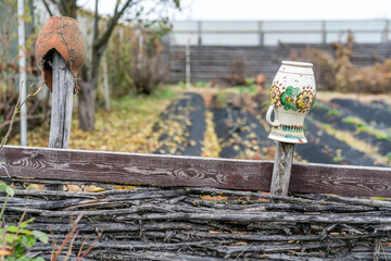 Broken clay pots on a wooden village fence © Andrzej
