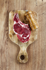 raw rib eye steak, cowboy steak, on a wooden chopping board, top view, no people,