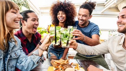 Multiracial friends cheering mojitos at bar restaurant - Young people celebrating happy hour...
