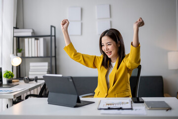 Excited asian businesswoman celebrating success while working on tablet