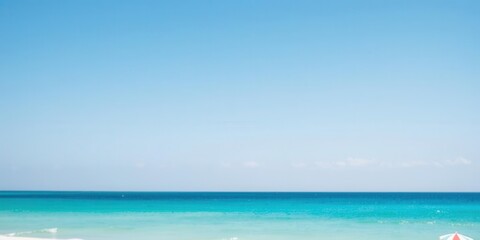 Obraz premium Sandy beach with turquoise ocean and clear blue sky on a sunny day, sea, horizon