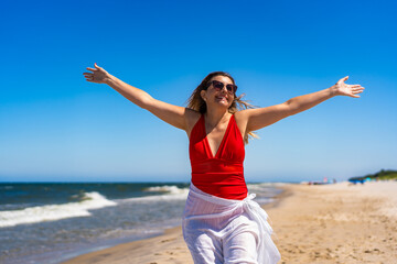 Summer vacation by Baltic Sea. Portrait of beautiful young woman in red swimsuit and white sarong...