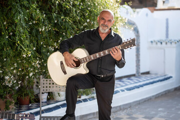 Senior man playing spanish guitar in his spanish patio