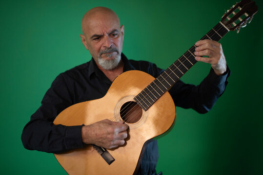 Senior 65 years old man playing spanish guitar