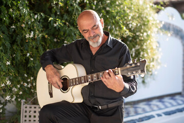 Senior man playing spanish guitar in his spanish patio