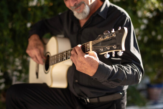 Man , 65 years old, playing guitar in the Andalusian courtyard of his home