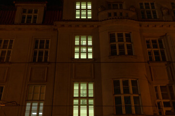 Obraz premium A breathtaking nighttime view showcases a building facade where illuminated windows accentuate the stunning architectural details, creating a captivating sight in the urban skyline at night