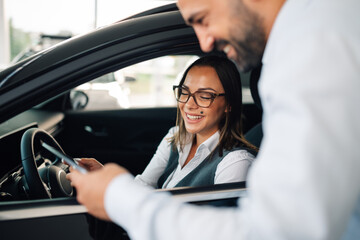 Modern car showroom scene with man and woman using a tablet