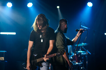 Guitarist and singer performing live on stage under blue lights