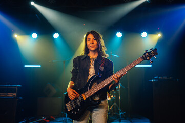 Female musician playing bass guitar on stage during concert