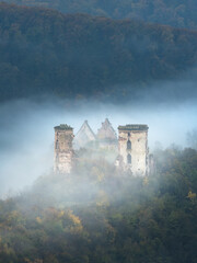portrait view to ruins of two towers of castle and church in morning fog