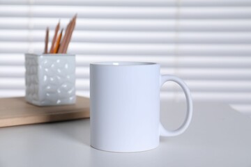 One blank ceramic mug and stationery on white table. Mockup for design