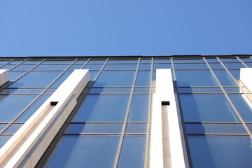 Fototapeta premium Exterior of modern building with many windows against light blue sky, low angle view