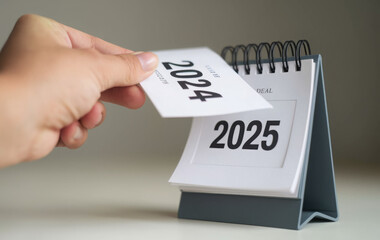 a woman's hand turns over a calendar sheet. year change from 2024 to 2025. 
