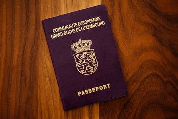 New Luxembourg passport on a brown-wood table, copy space