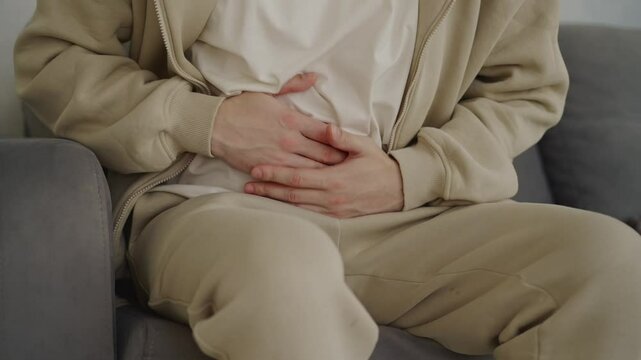 Abdominal pain.
Severe cramp in the stomach.
A person has a diseased intestine.
A man sits on the sofa and suffers from stomach pain.
Severe pain worries the guy
