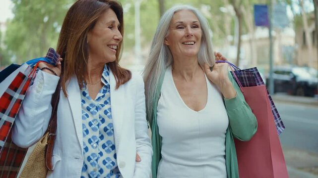 Beautiful senior women bonding outdoors in the city - Attractive cheerful mature female friends having fun, shopping and bonding, concepts about elderly lifestyle	