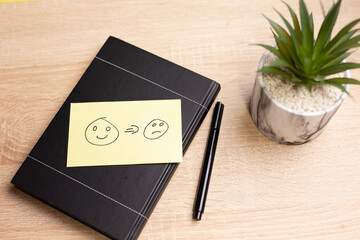 Sticky note showing mood change from happy to sad on a notebook